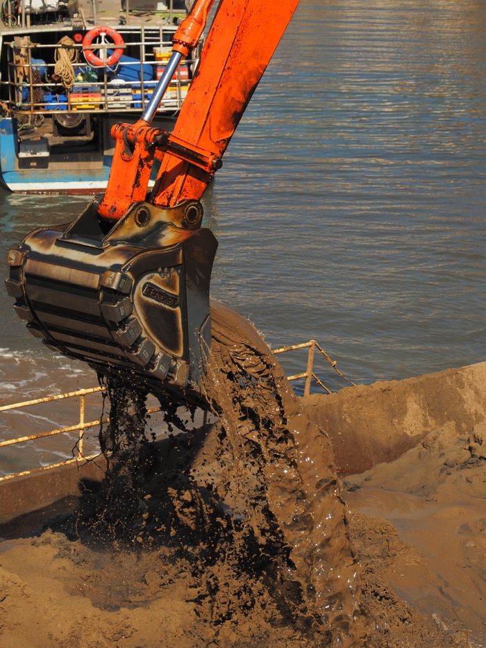 An excavator performing dredging operations in Scarborough harbor, England. Industrial and construction activity.